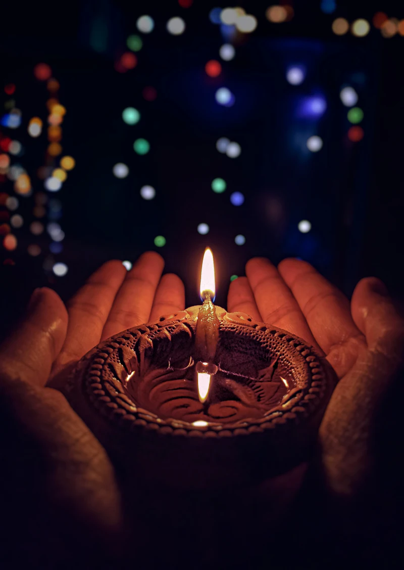 Hands holding a lit diya