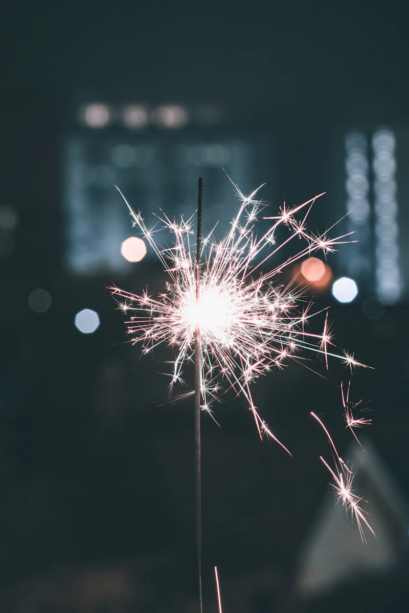 Sparkler glowing against a teal night